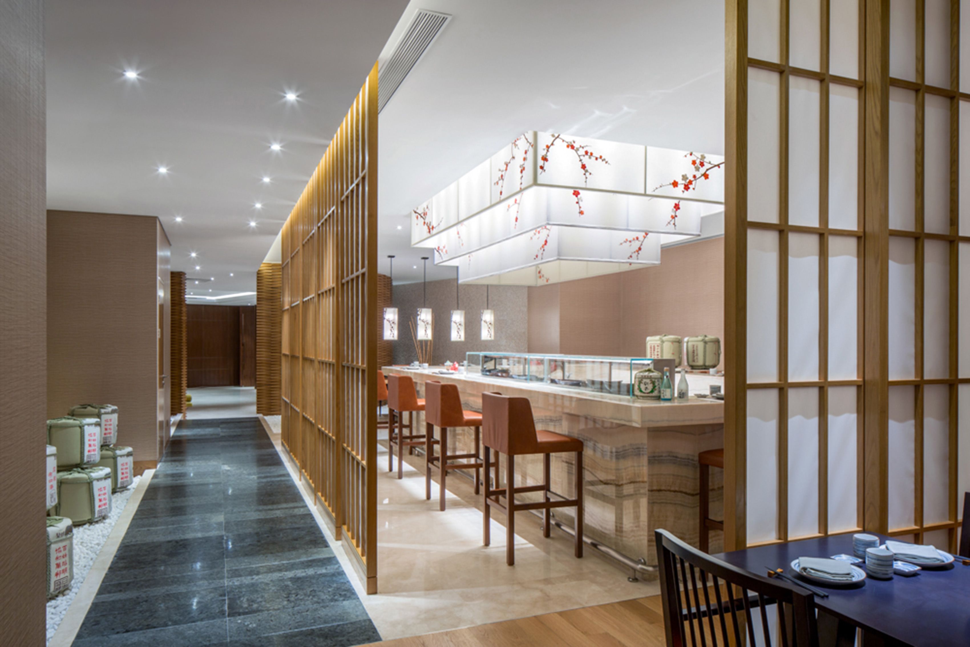 A modern hotel lobby with a long corridor, wooden partitions, and a reception area with a counter and chairs.