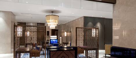 A modern lobby with a reception desk, seating area, and decorative screens.