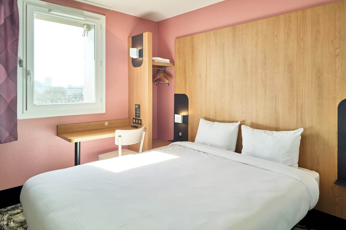 A hotel room with a large bed, a desk, and a wardrobe.