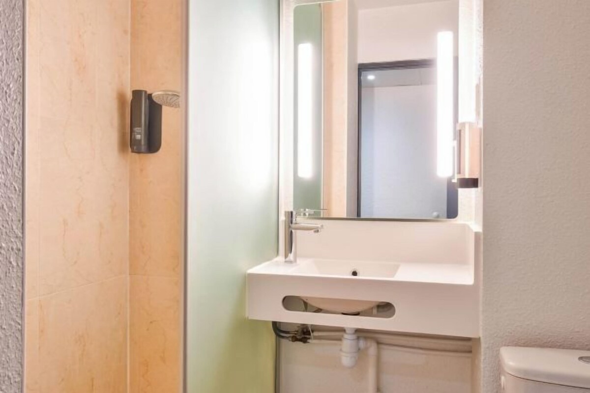 A bathroom with a white sink, a mirror, and a toilet.