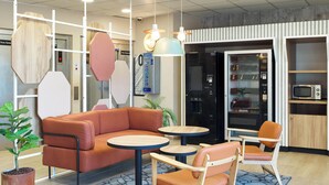 A modern interior with a sofa, two chairs, a coffee table, and a microwave. - B&B HOTEL Paris Porte de la Villette (Aubervilliers)