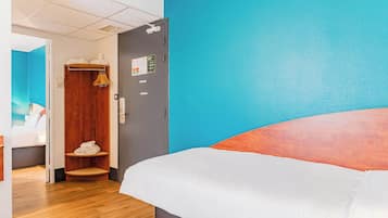 Een hotelkamer met een bed, een houten kledingkast, een badkamer en een blauwe wand.