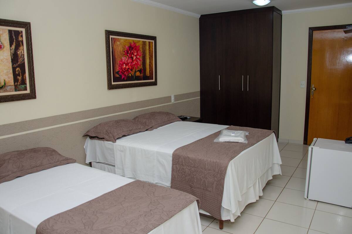 A hotel room with two beds, a wardrobe, and a desk.