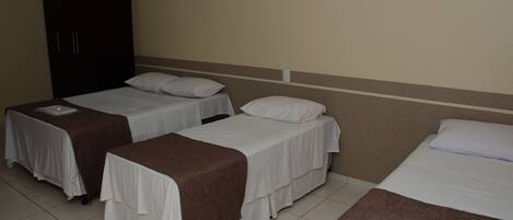 A hotel room with two single beds, a wardrobe, and a tiled floor.