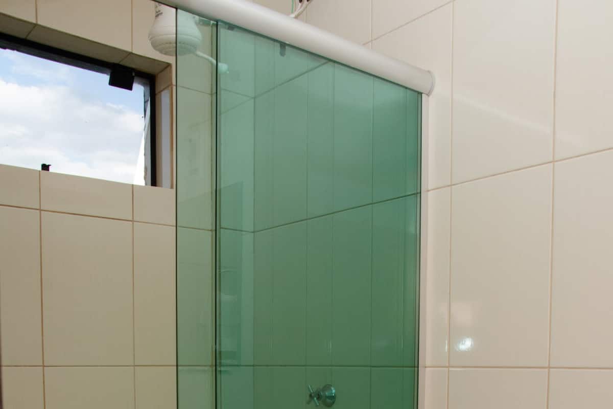 A bathroom with a glass-enclosed shower, a white toilet, and a visible window.