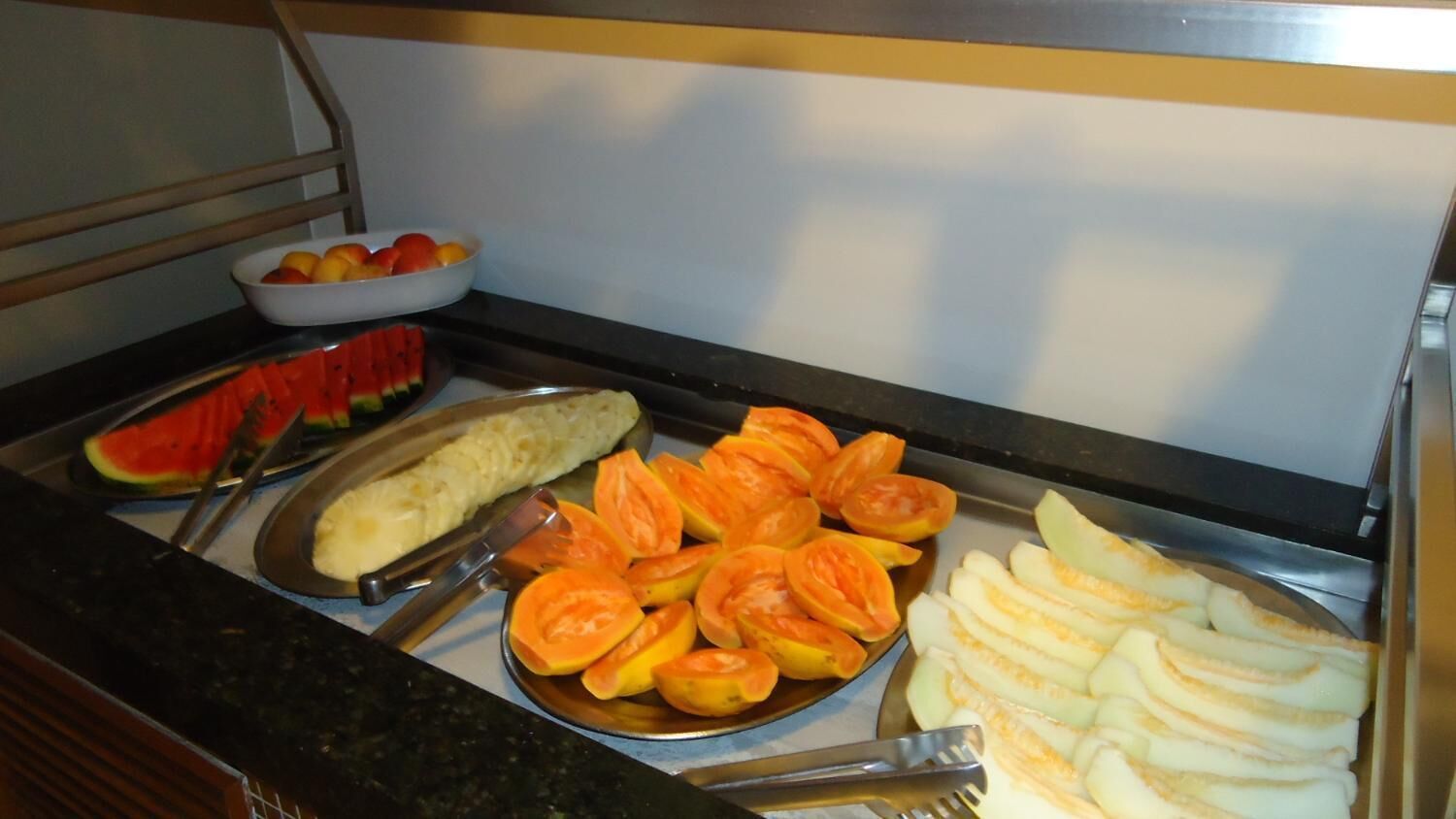 Un buffet proposant des fruits et des légumes coupés en tranches, notamment de la pastèque, de l’ananas et des tomates.