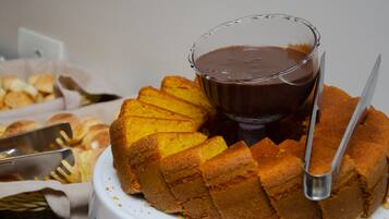 A cake with a glass of chocolate sauce on a white plate.