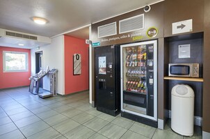 A hotel lobby with vending machines, a microwave, and a trash bin.