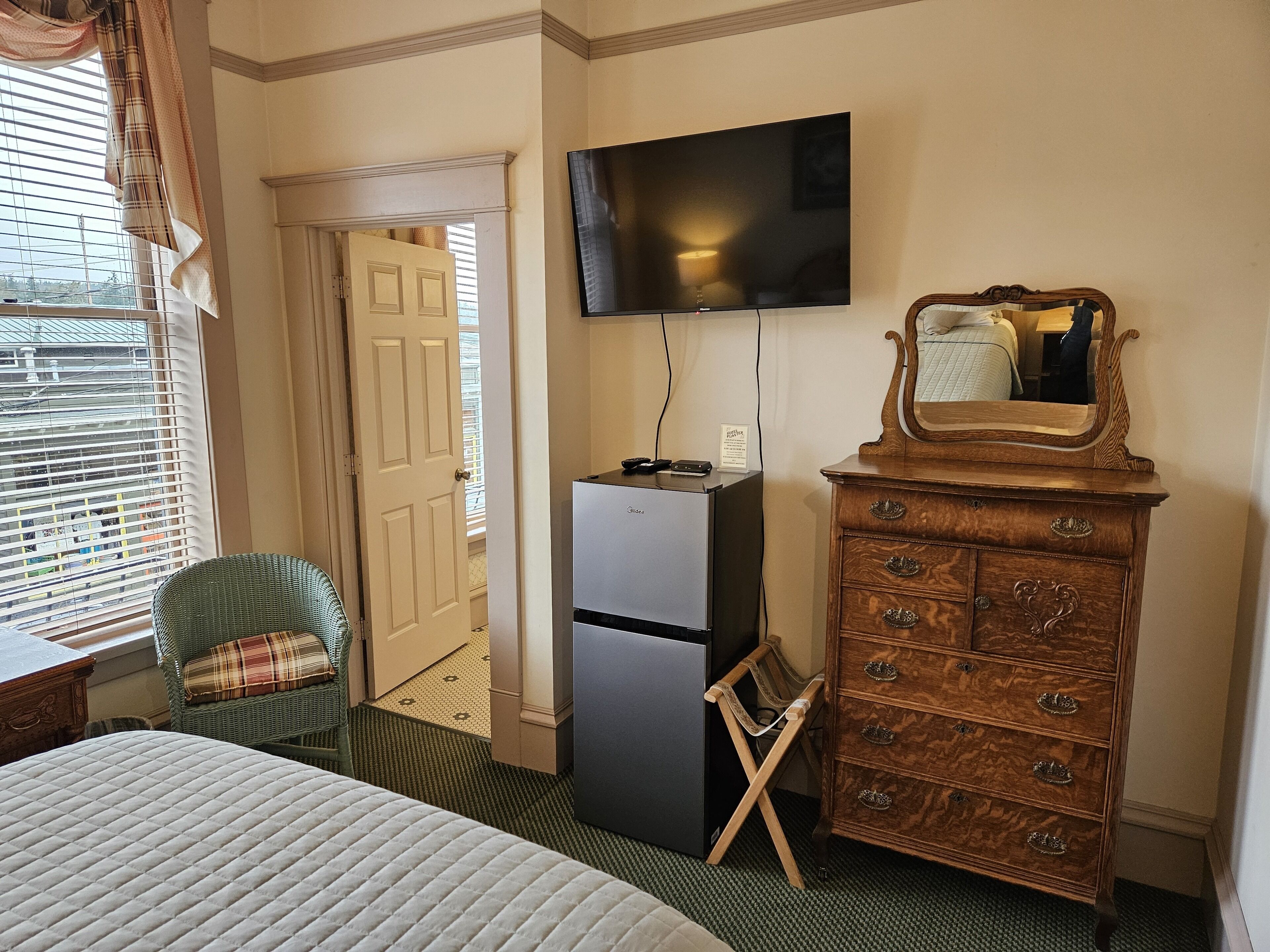 Une chambre d’hôtel comprenant un lit, une commode, un téléviseur et une porte donnant sur une autre pièce.