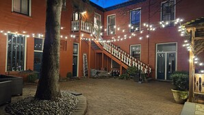 A brick building with a staircase, string lights, and outdoor seating.
