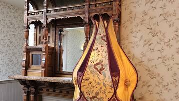 A room with a wooden staircase, a patterned wallpaper, and a decorative hanging.