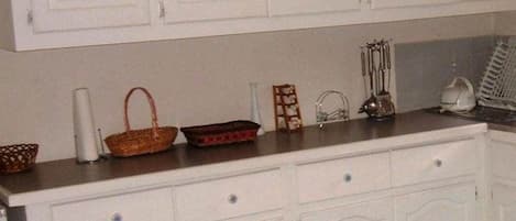A kitchen with white cabinetry, a countertop, and various kitchen items.