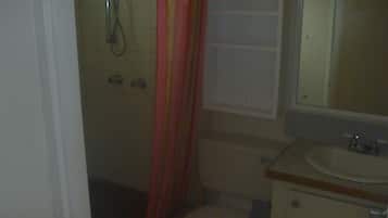 Uma casa de banho pequena com sanita, lavatório e chuveiro.