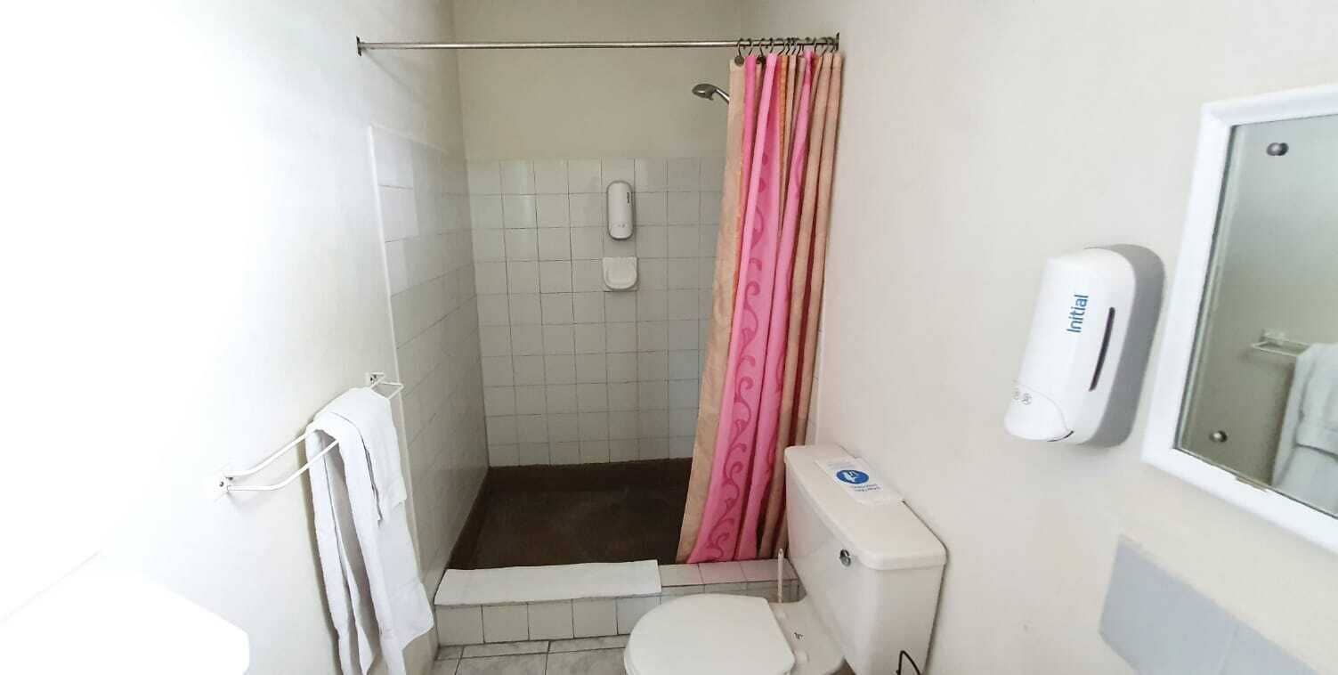 Un baño pequeño con ducha, inodoro y dispensador de jabón.
