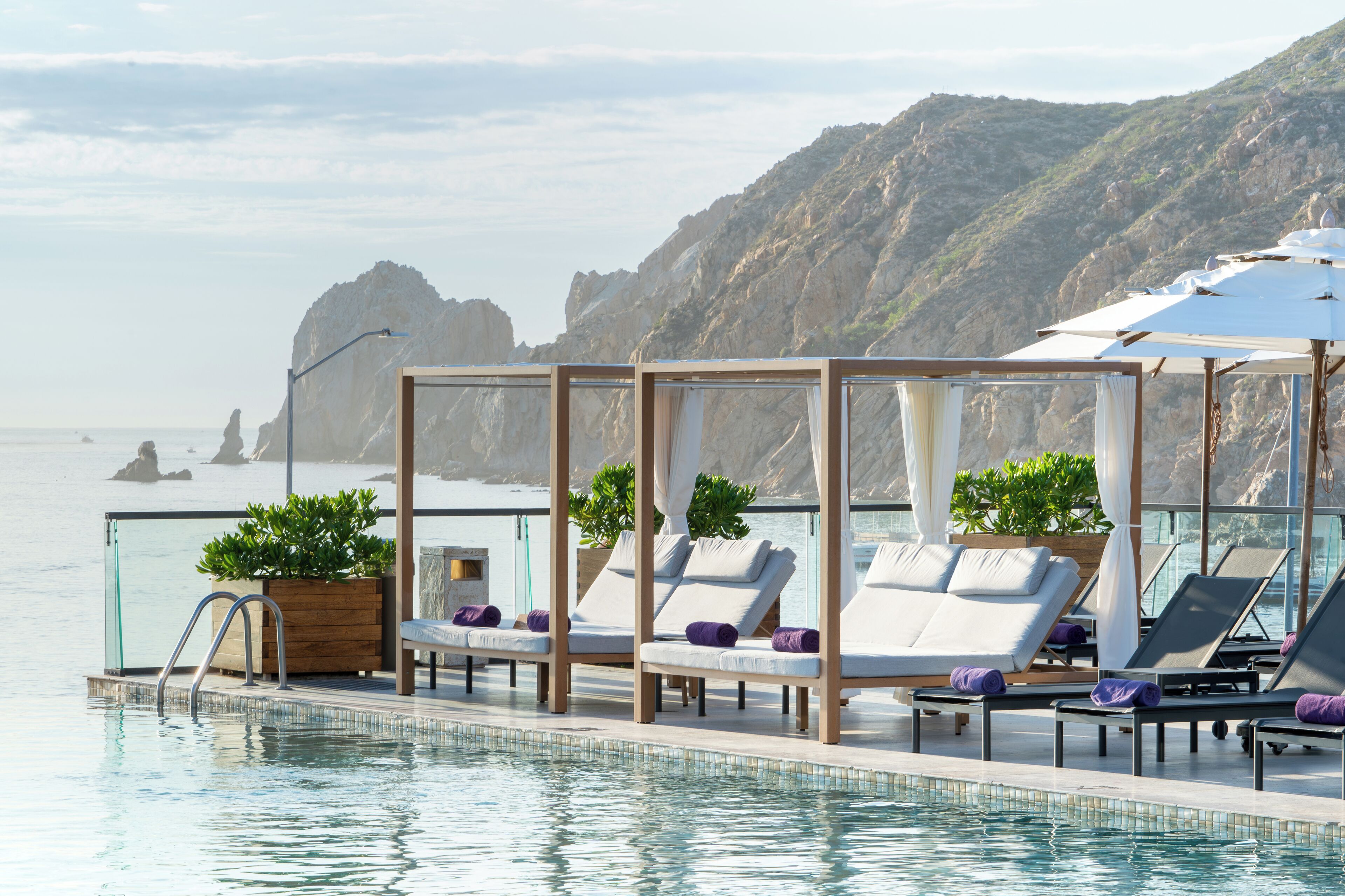 A poolside area with lounge chairs and a view of the sea.