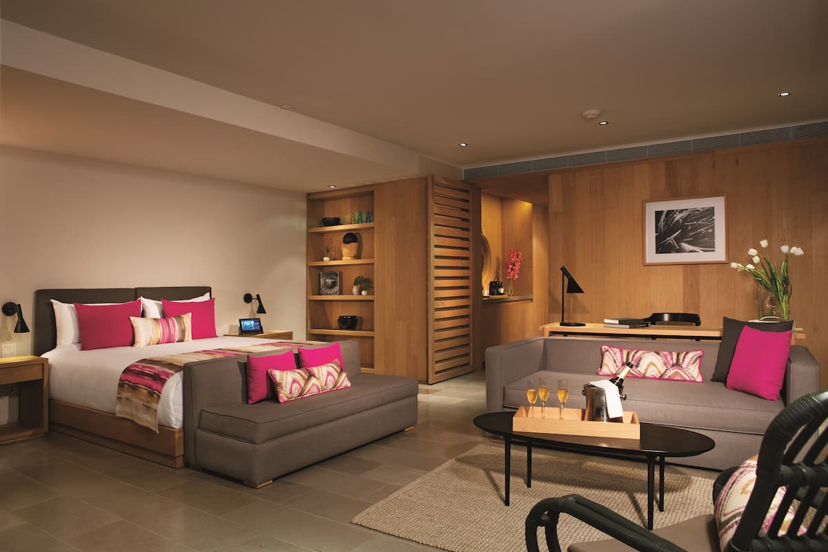 Una habitación de hotel moderna con una cama grande, un sofá, un escritorio y una estantería.