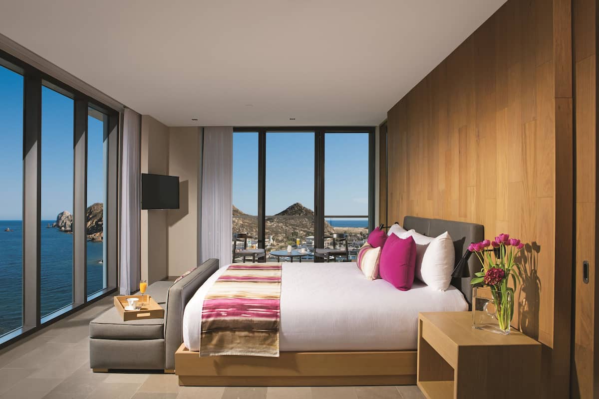 Una habitación de hotel moderna con una cama grande, un área de estar y vistas al mar.