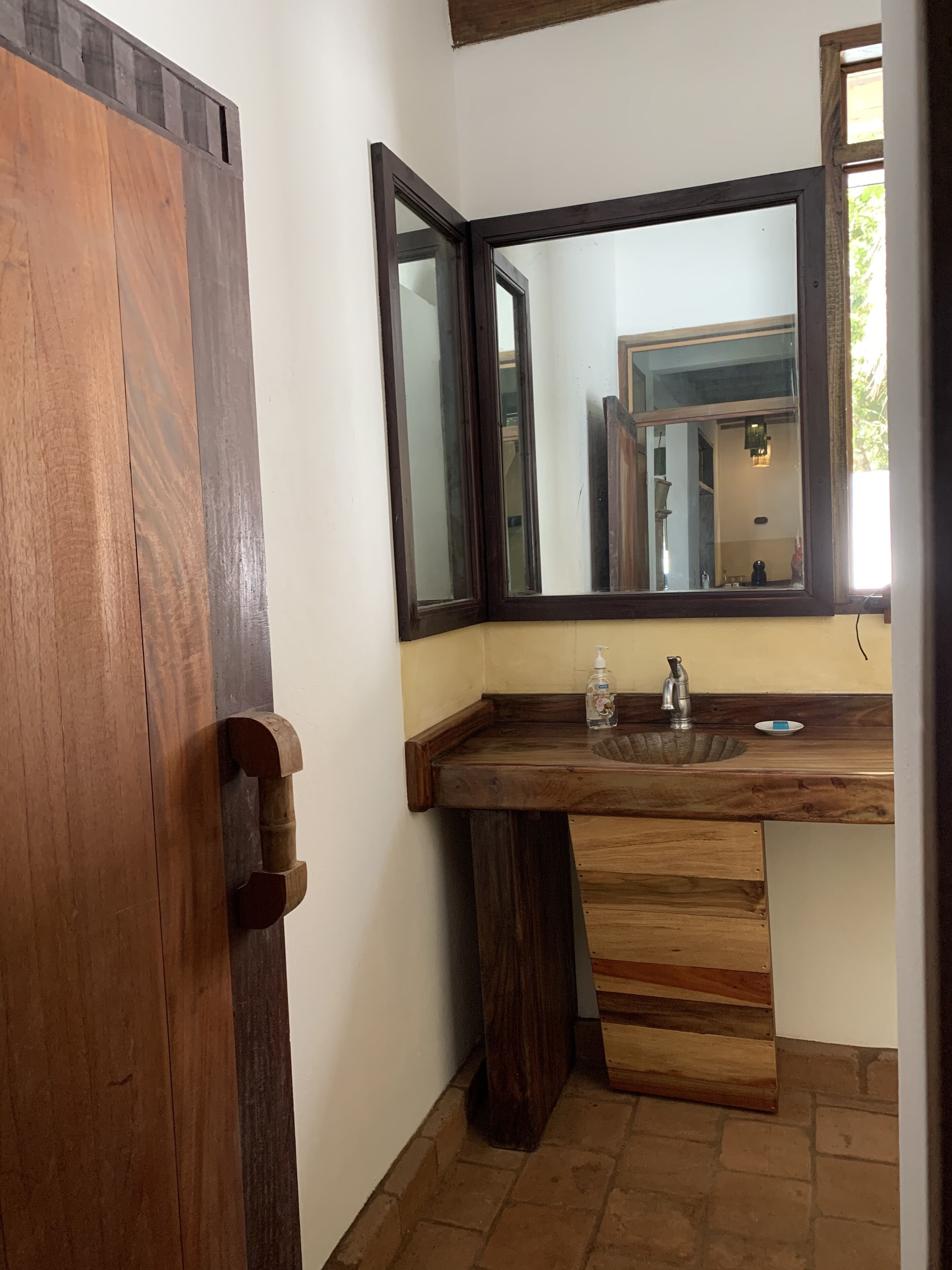 A bathroom with a wooden vanity, a large mirror, and a sink.