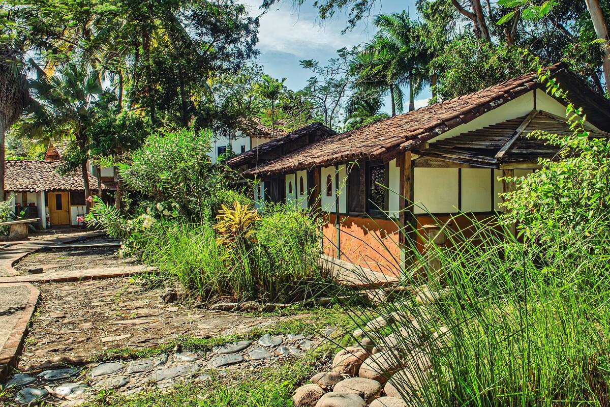 A rustic village with traditional houses, a stone pathway, and lush greenery.