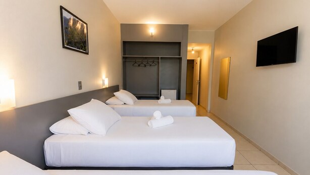 Een hotelkamer met twee bedden, een kledingkast, een televisie en een schilderij aan de muur.