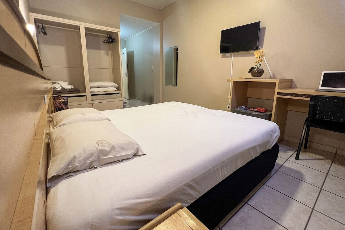 Une chambre d’hôtel équipée d’un lit, d’un bureau, d’une télévision et d’une armoire.