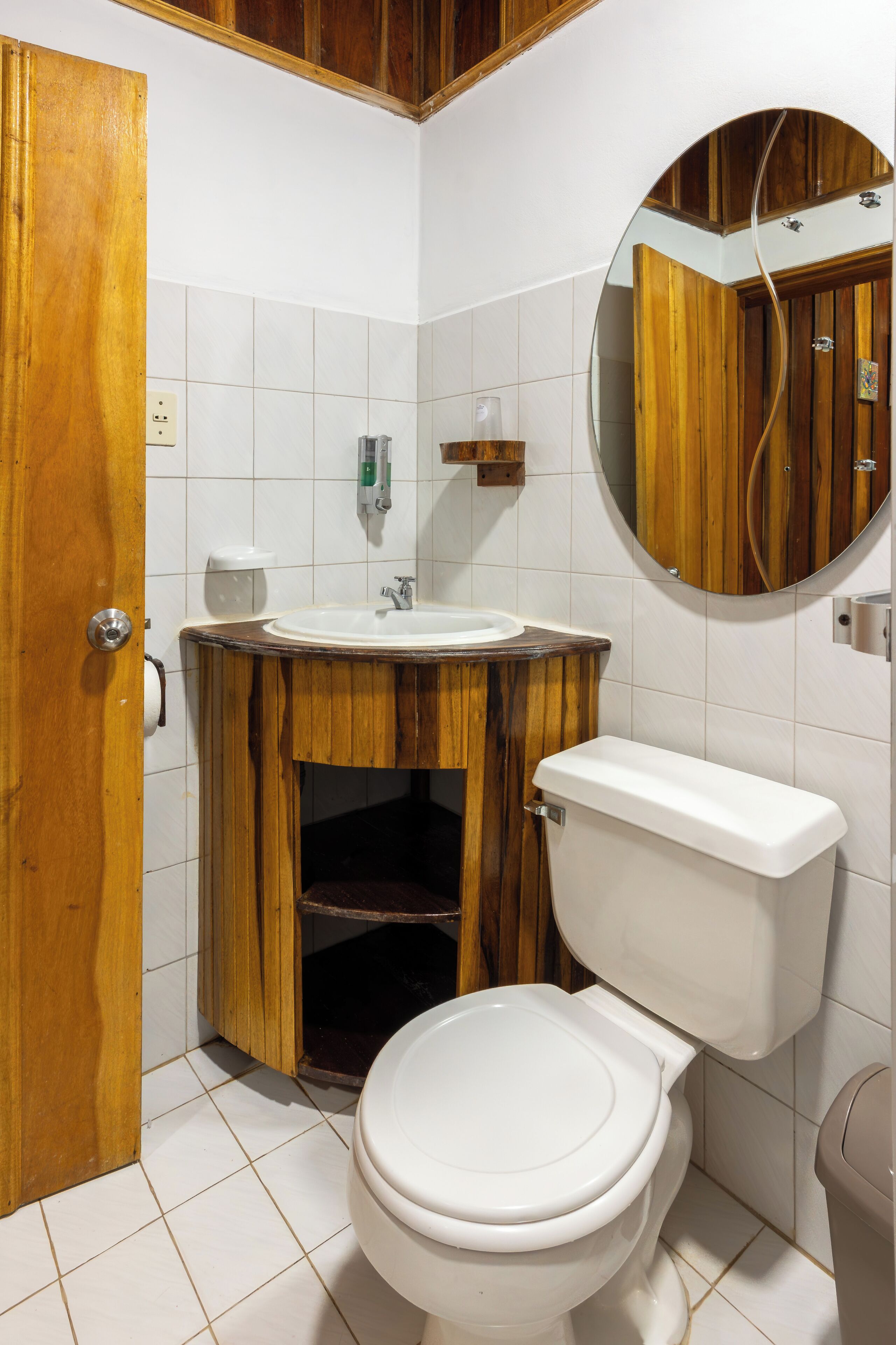 Un bagno con un mobile vanitario in legno, un water bianco e uno specchio sopra il lavandino.
