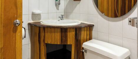 Un bagno con un mobile vanitario in legno, un water bianco e uno specchio sopra il lavandino.
