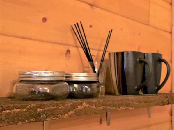 Una encimera de cocina con un vaso metálico, un tarro de vidrio y un recipiente con tapa metálica.