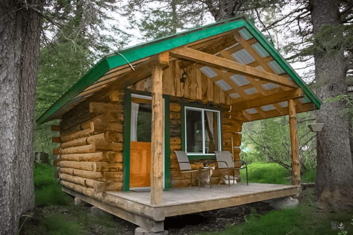 A log cabin with a porch, a window, and a door.