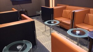 A hotel lobby with orange seating areas, small round tables, and a flat-screen TV mounted on the wall. - My Dear - Adults Only (Osaka)