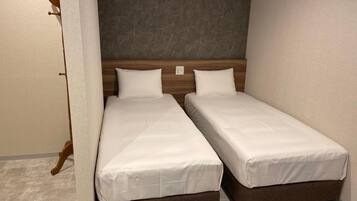 A double bed with a wooden headboard and white bedding in a room with a grey marble floor.