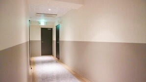 A narrow hallway with a carpeted floor, white walls, and a door at the end. - My Dear II - Adults Only (Osaka)