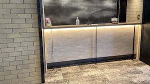 A reception desk with a marble top, a black-framed mirror, and a small shelf with a bottle and a magazine. - My Dear II - Adults Only (Osaka)