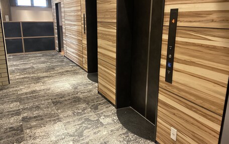 A modern elevator with a control panel and a wooden wall.