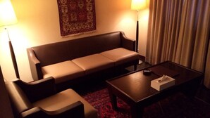 Una habitación de hotel con sofá, una mesita de centro y dos lámparas.