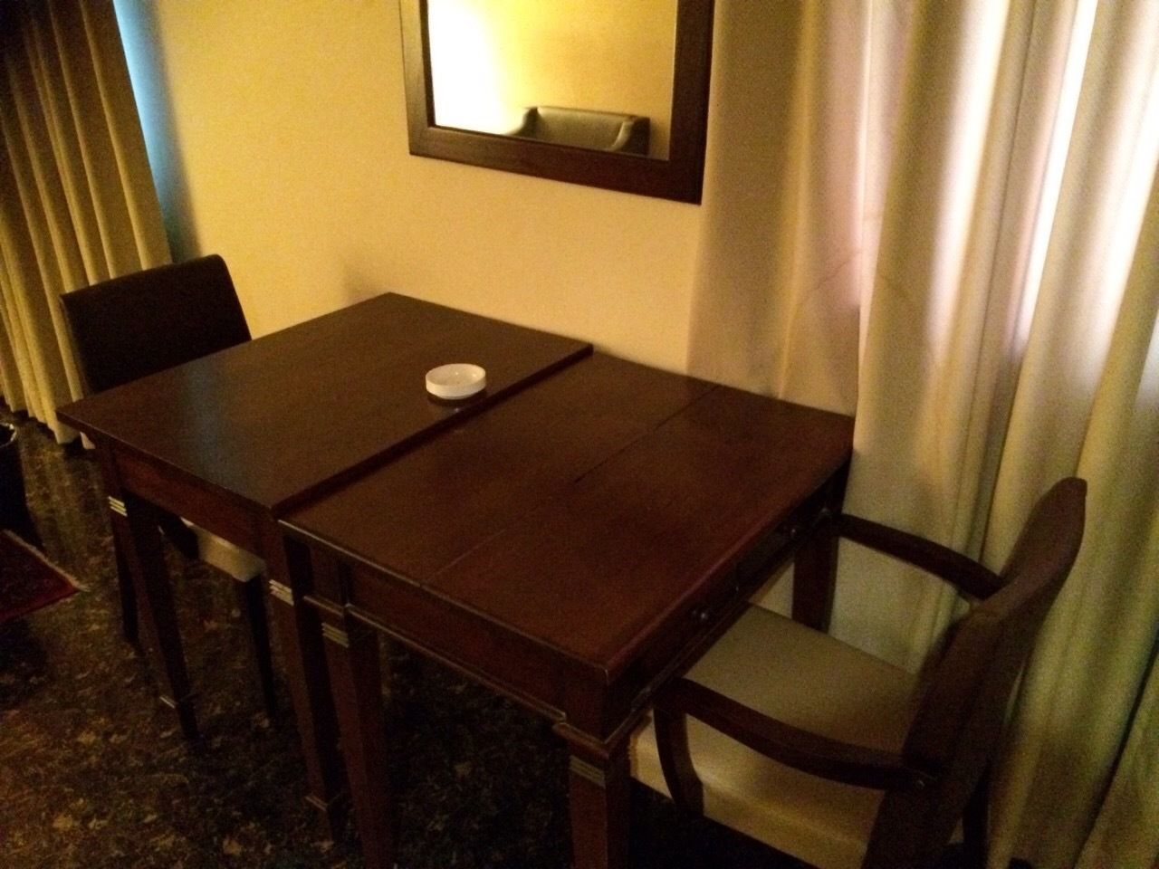 A hotel room with a wooden table and four chairs.