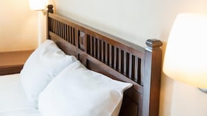 Una cama con cabecera de madera y dos almohadas blancas.