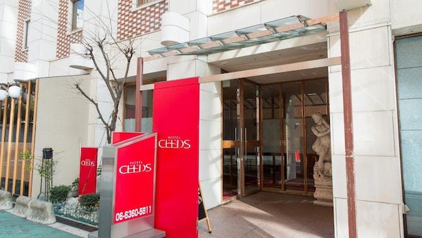 Entrada de hotel con un letrero rojo, puertas de vidrio y una estatua.