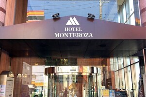 La entrada del Hotel Monterozá, con un moderno frente de vidrio y un logotipo destacado.