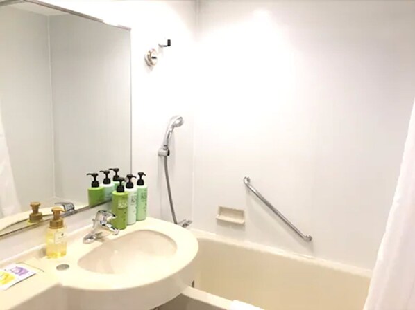 Un baño con lavabo, espejo, ducha y barras de apoyo.