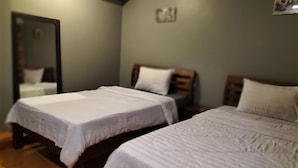 A room with two single beds, a wooden headboard, a mirror, and a wall-mounted picture. - Sovanphum Guesthouse (Phnom Penh)