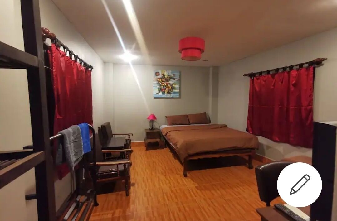 A bedroom with a bed, a desk, a chair, a lamp, and a painting on the wall.