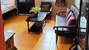 A living room with a sofa, a coffee table, and a sliding door. - Sovanphum Guesthouse (Phnom Penh)