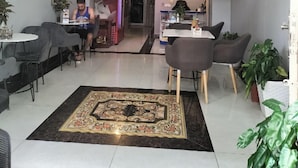 A dining area with tables and chairs, a decorative rug, and potted plants. - Sovanphum Guesthouse (Phnom Penh)