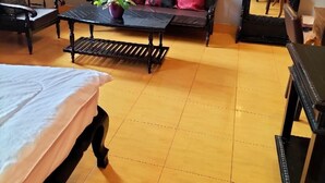 A room with a sofa, a small table with a plant, a bed, and a large mirror. - Sovanphum Guesthouse (Phnom Penh)