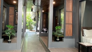 Un couloir avec un ventilateur de plafond, des plantes en pot et un coin salon comprenant un canapé et une table.
