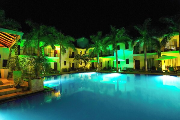 Relax by the pool surrounded by palm trees and lounge chairs.