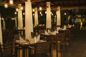 Formal dining area with elegant white pillars and wooden beams, featuring tables set with fine linens and glassware.