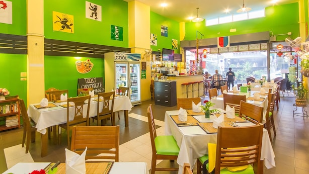 A restaurant with green walls, wooden tables, and chairs. There are signs on the walls and a counter with a menu. - Aree 's House (Hua Hin)