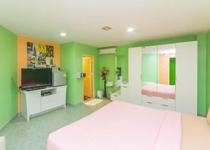 Un dormitorio con cama, televisor, armario y un pequeño escritorio.